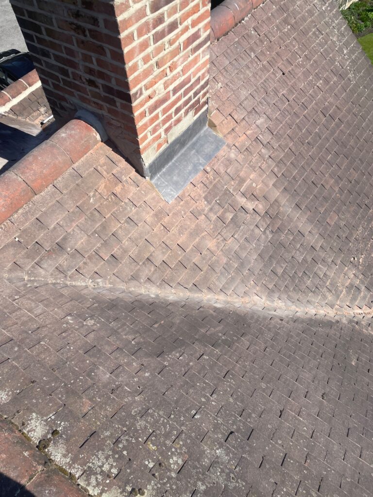 Weathered tiled roof beside a chimney before an upgrade