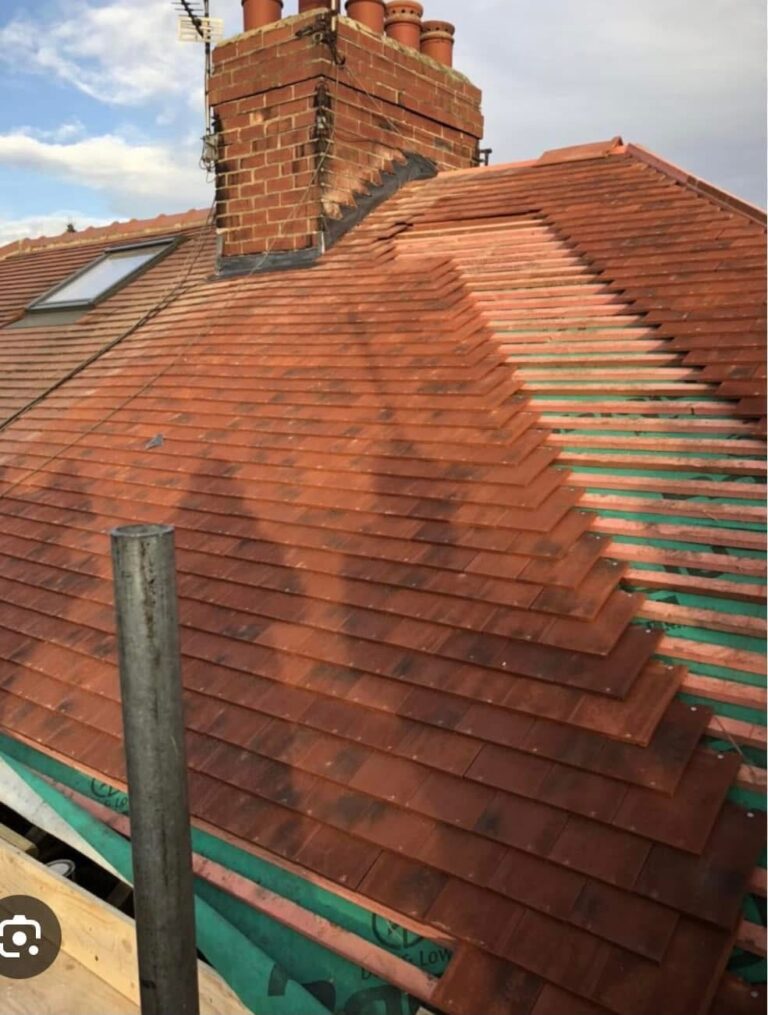 Newly tiled red hip roof with chimney